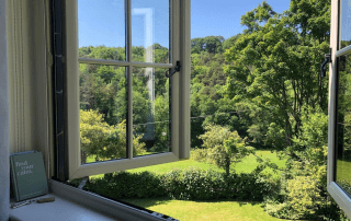 Countryside garden view through open window overlooking trees and lawn