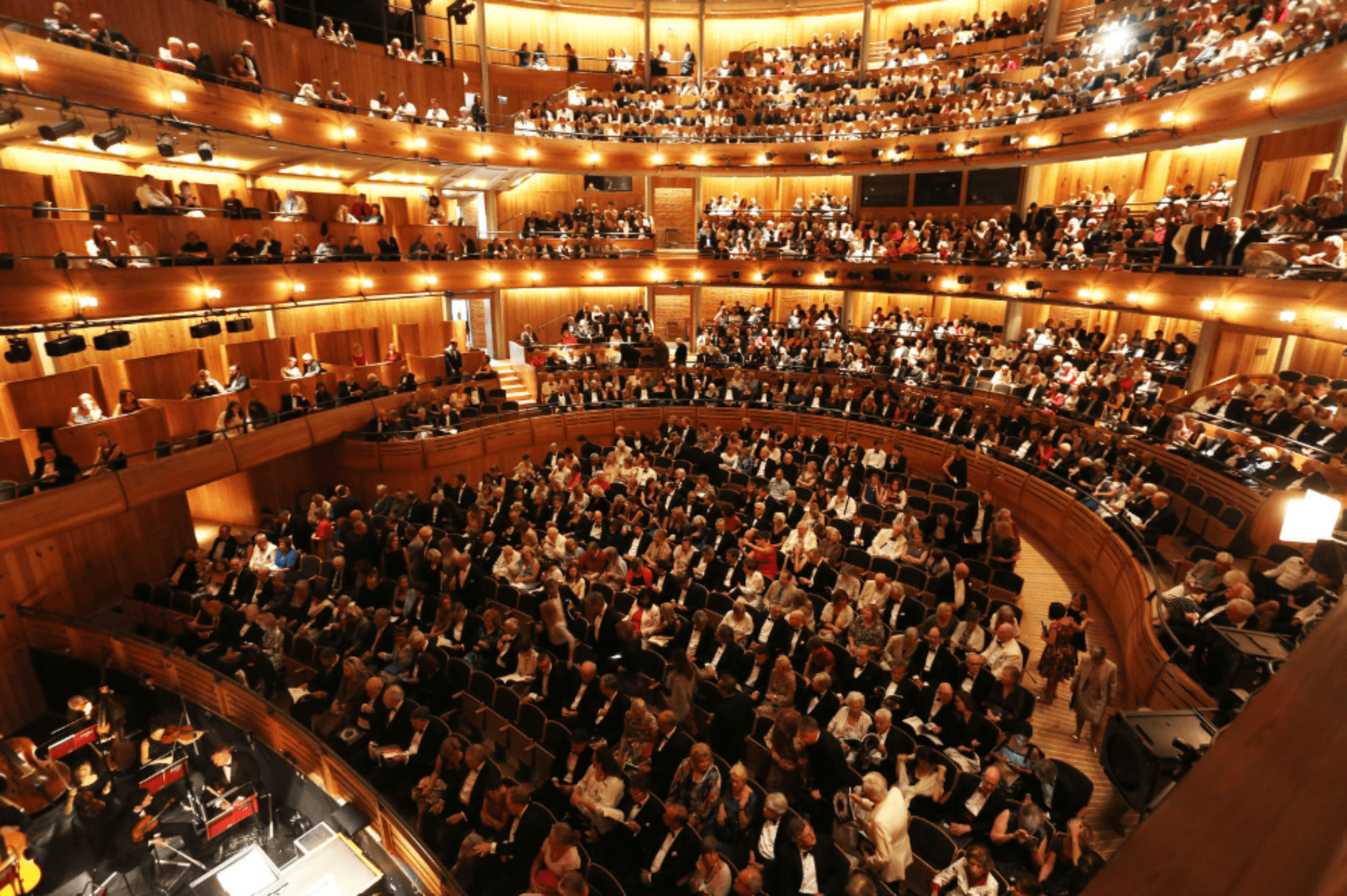 Audience seated inside a large modern opera house auditorium before a performance