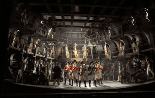 Large ensemble opera scene on stage with performers in historical military costumes