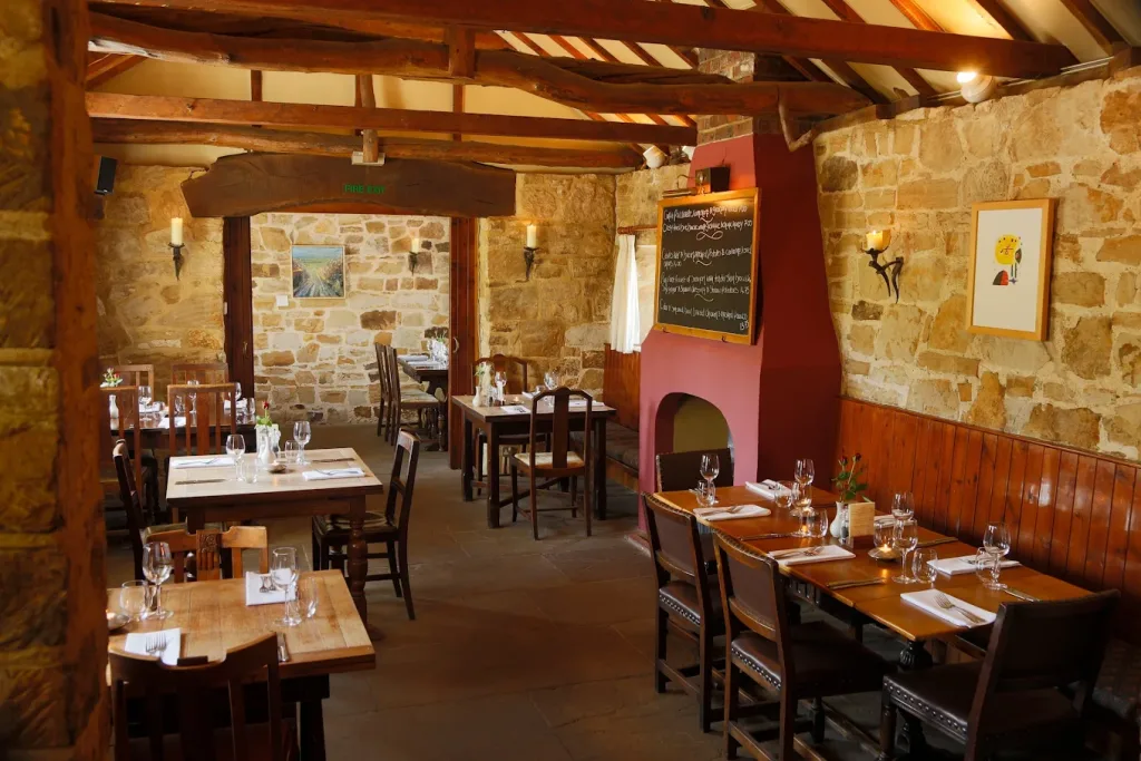 Rustic restaurant interior with wooden beams, stone walls and neatly set dining table