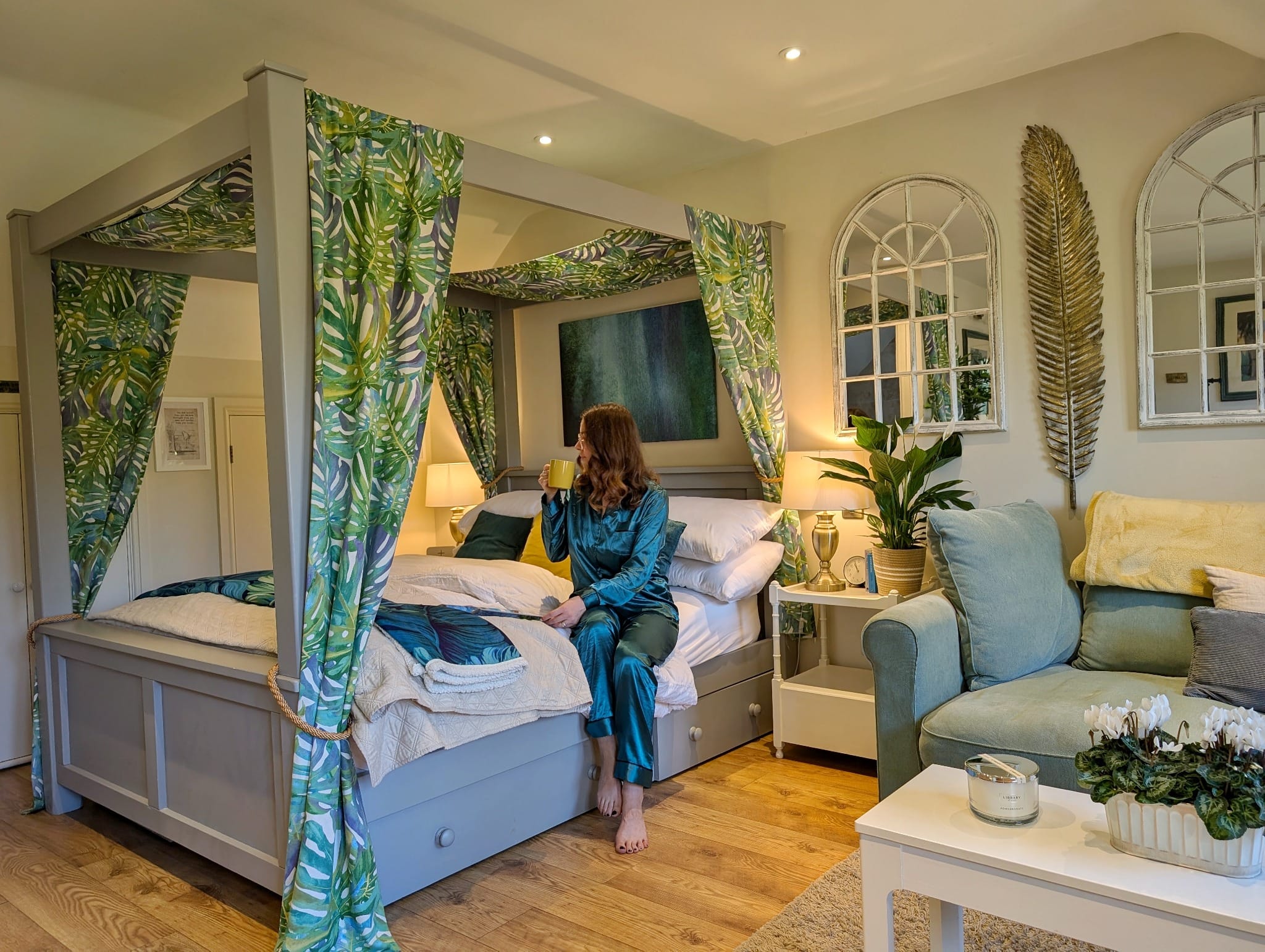 Woman relaxing on canopy bed in stylish bedroom with tropical décor and soft lighting