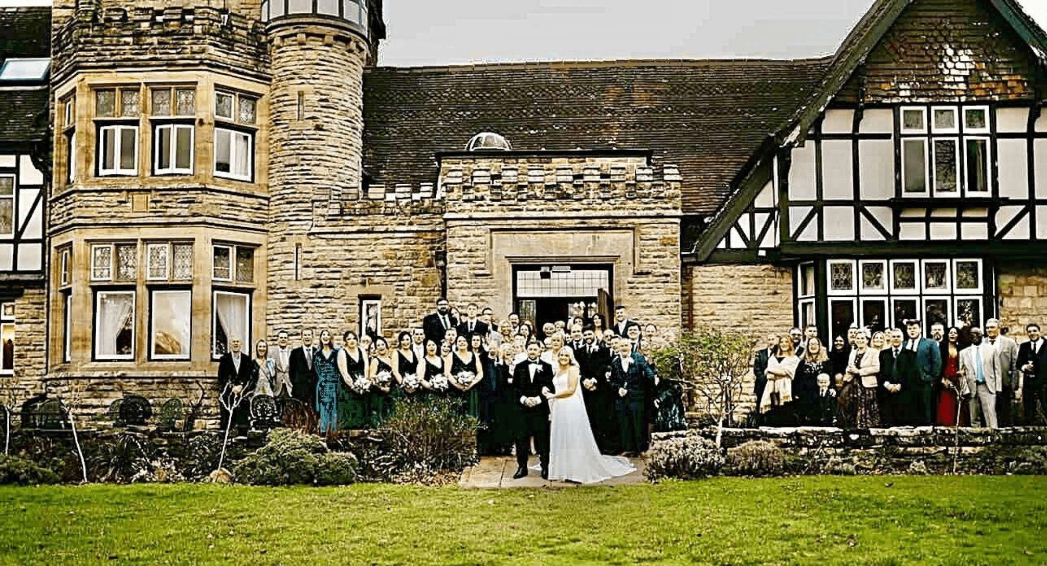 Large wedding group photo outside historic stone manor venue